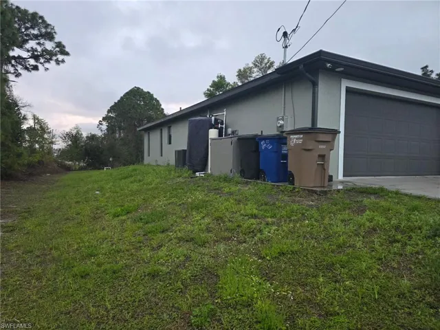 View of property exterior with stucco siding and a lawn