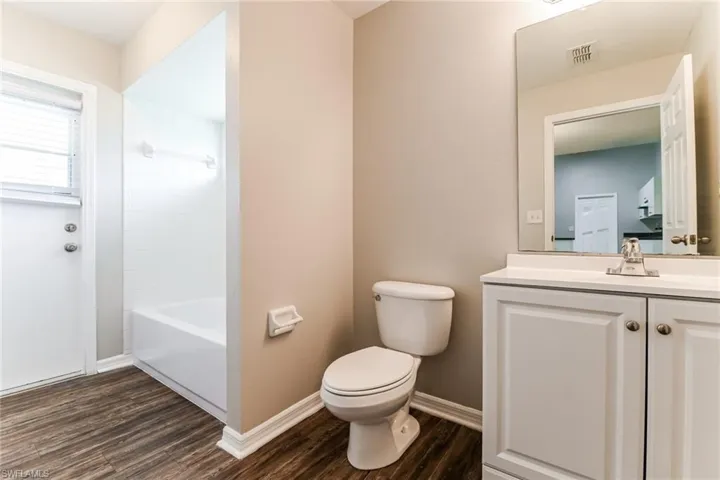 Bathroom with vanity, dark wood-type flooring, and washtub / shower combination