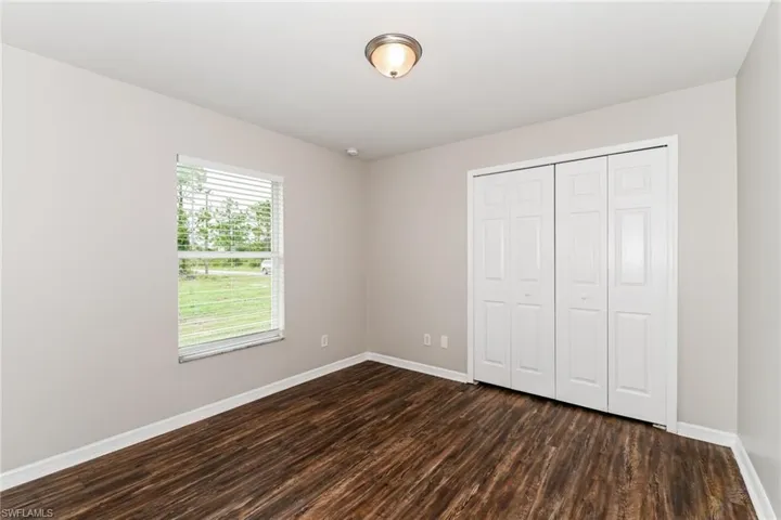 Unfurnished bedroom with a closet and dark wood-style floors