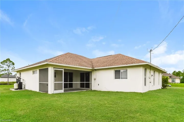 Back of property featuring stucco siding, a yard, a shingled roof, and a sunroom