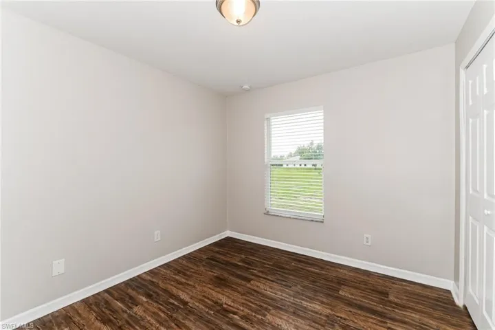 Unfurnished bedroom featuring a closet and dark wood finished floors