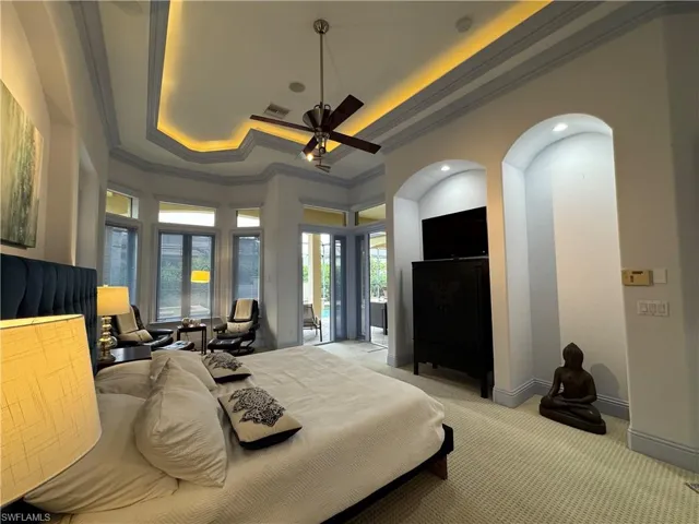 Bedroom with ornamental molding, a tray ceiling, light colored carpet, and baseboards