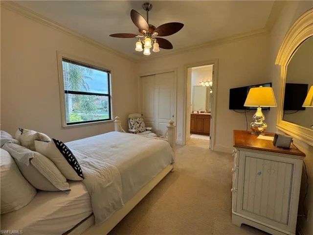 Bedroom with light carpet, ornamental molding, ensuite bathroom, and baseboards