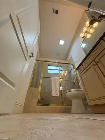 Bathroom with tiled shower, visible vents, and crown molding
