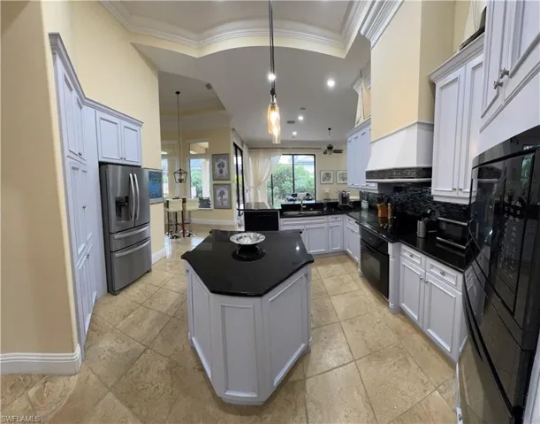 Kitchen with black appliances, dark countertops, a kitchen island, and decorative light fixtures