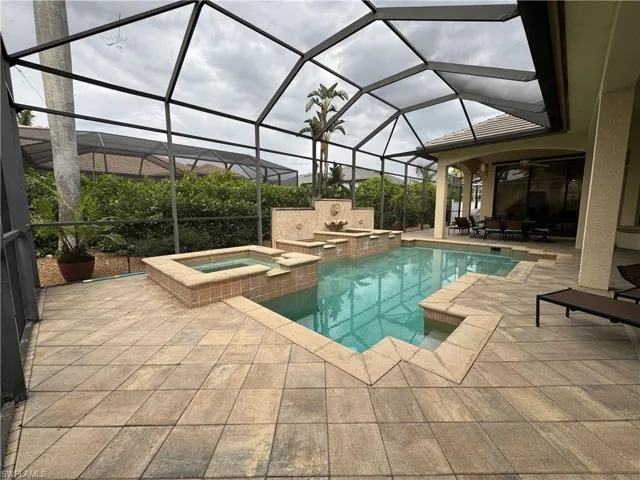 View of swimming pool featuring glass enclosure, a pool with connected hot tub, ceiling fan, and a patio