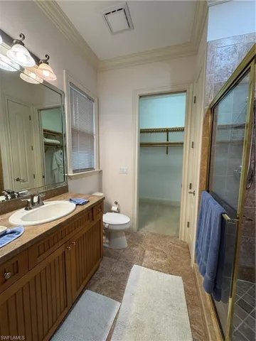 Full bathroom featuring vanity, visible vents, a spacious closet, ornamental molding, and a shower stall