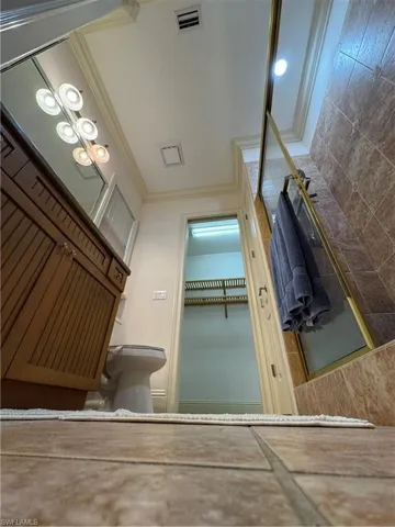 Bathroom with toilet, visible vents, ornamental molding, and a walk in closet