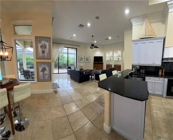 Kitchen featuring a sink, white cabinets, tasteful backsplash, dark countertops, and crown molding