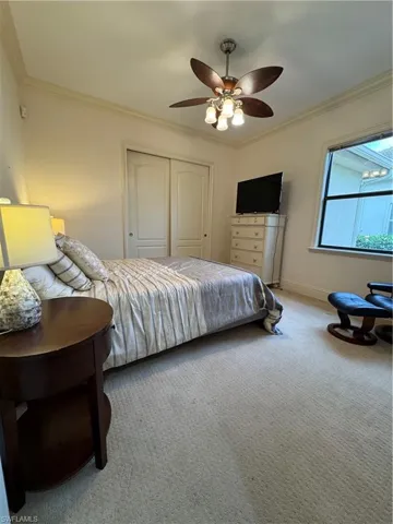 Bedroom featuring carpet flooring, a ceiling fan, baseboards, ornamental molding, and a closet