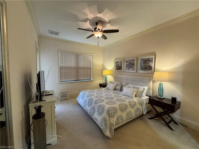 Bedroom featuring light carpet, baseboards, visible vents, and ornamental molding