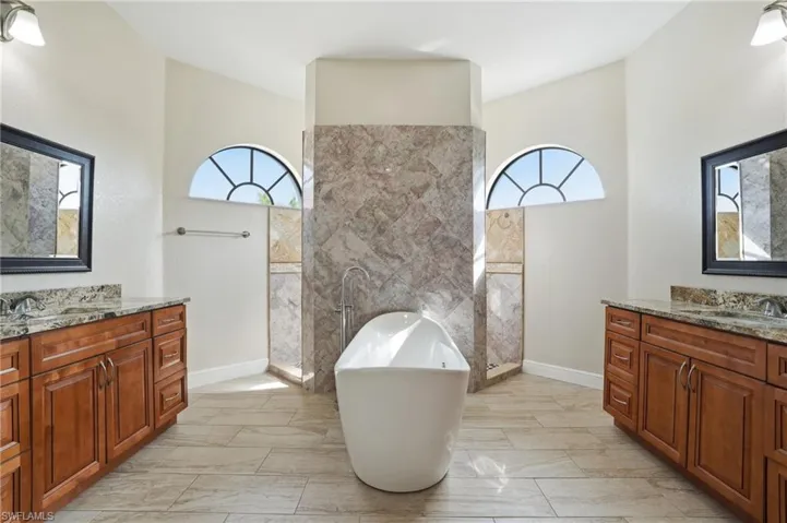 Primary Bathroom with a freestanding bath, two vanities, plenty of natural light, and walk in shower
