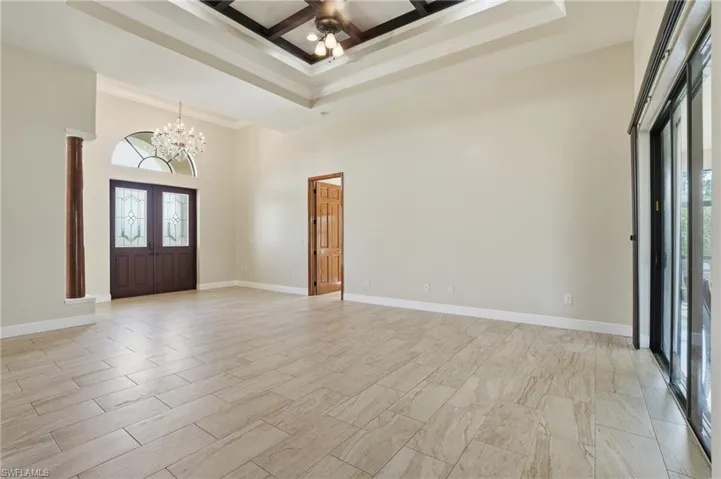 Foyer entrance featuring a towering ceiling, coffered ceiling, healthy amount of natural light, a chandelier, and ornamental molding