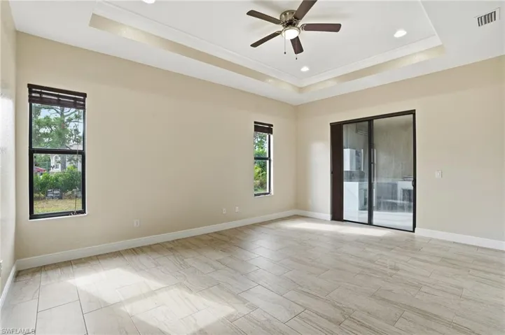 Primary featuring a tray ceiling, crown molding, a ceiling fan, and recessed lighting