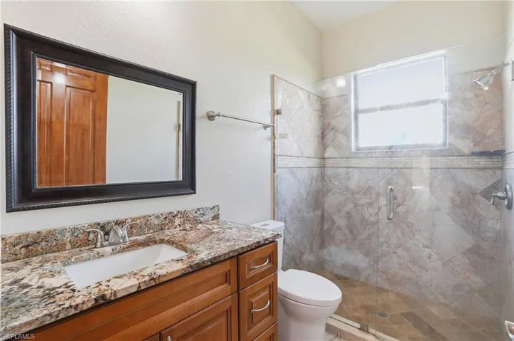 Bathroom with vanity, a stall shower, and a textured wall