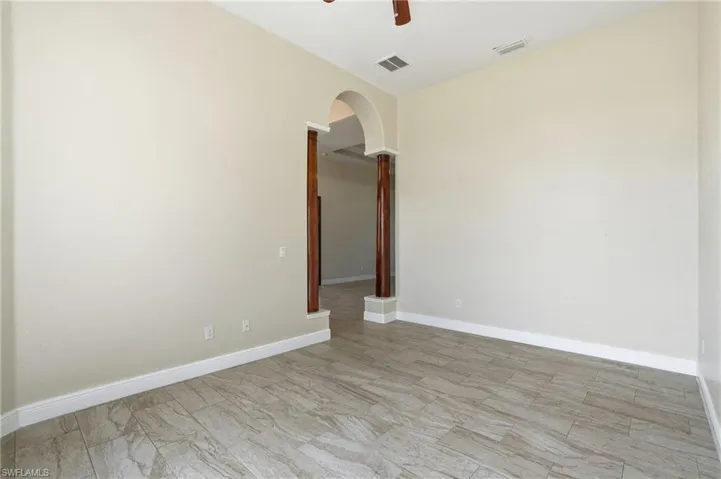 Den featuring arched walkways and a ceiling fan