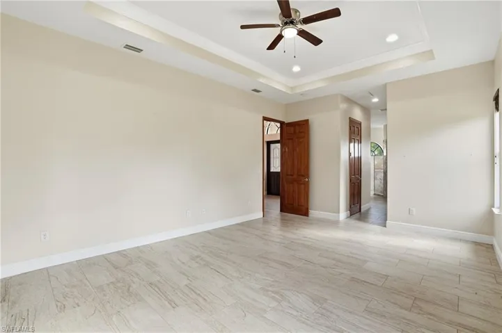 Primary with a raised ceiling, recessed lighting, and a ceiling fan
