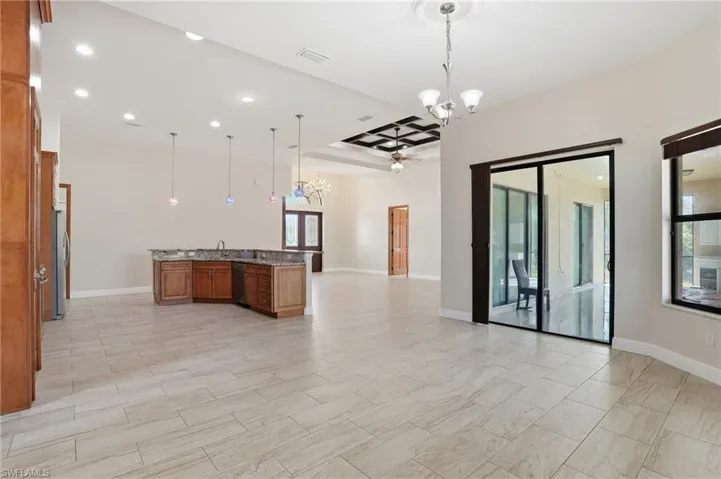 Kitchen featuring pendant lighting, a chandelier, brown cabinetry, open floor plan, and dark stone counters