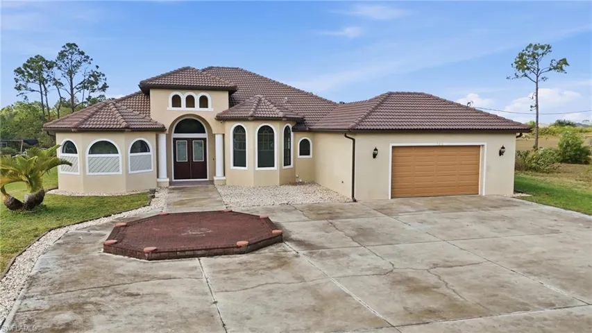 Mediterranean / spanish home with concrete driveway, stucco siding, an attached garage, and a tiled roof