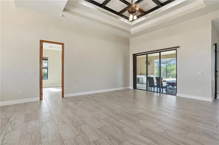 Living Room with a towering ceiling, coffered ceiling, ornamental molding, beam ceiling, and ceiling fan