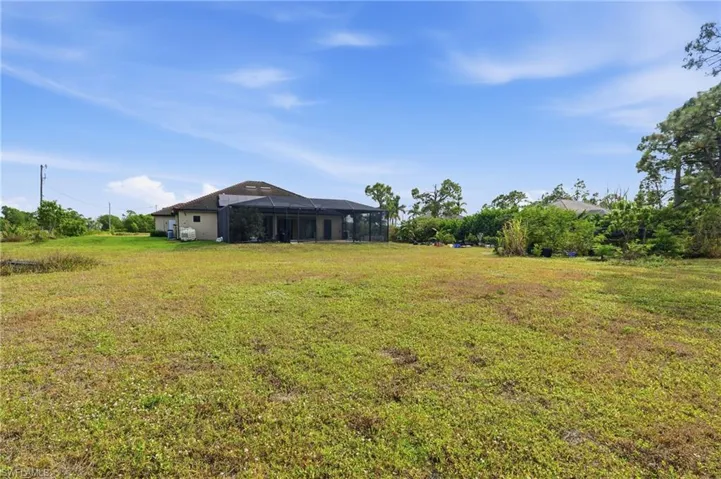 View of grassy yard featuring a sunroom and a lanai