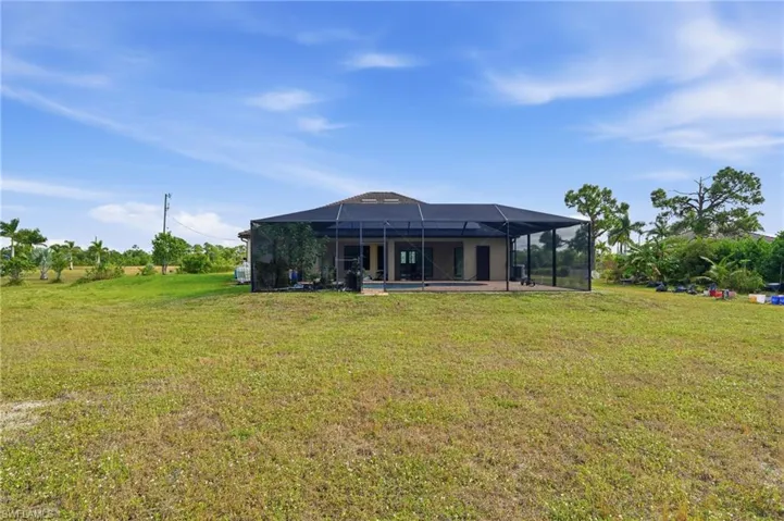 Back of house featuring a lanai, a lawn, and a sunroom