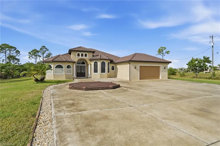 Mediterranean / spanish house with a front yard, driveway, stucco siding, a garage, and a tiled roof