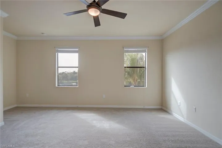 Empty room featuring light carpet, crown molding, and a ceiling fan