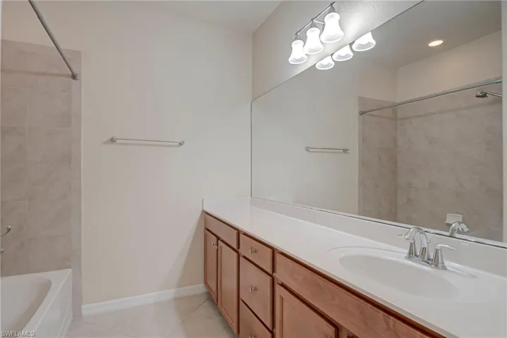 Full bath featuring shower / bathtub combination, vanity, and light tile patterned floors