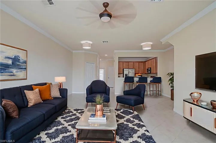 Living area with ornamental molding, ceiling fan, and light tile patterned floors