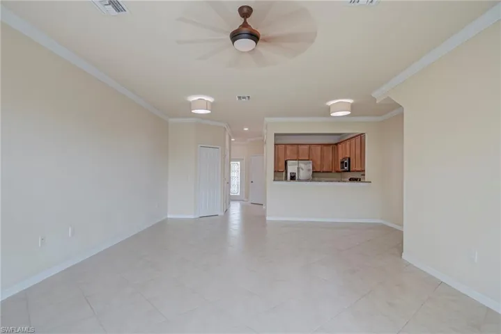 Unfurnished living room with crown molding, a ceiling fan, and light tile patterned floors