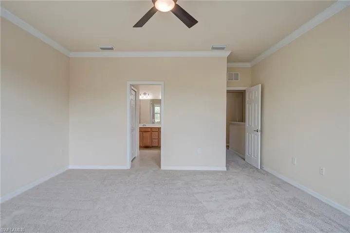 Unfurnished bedroom featuring crown molding, light carpet, ceiling fan, and connected bathroom