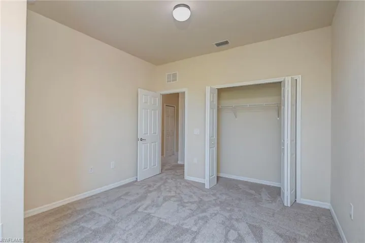 Unfurnished bedroom with light colored carpet and a closet