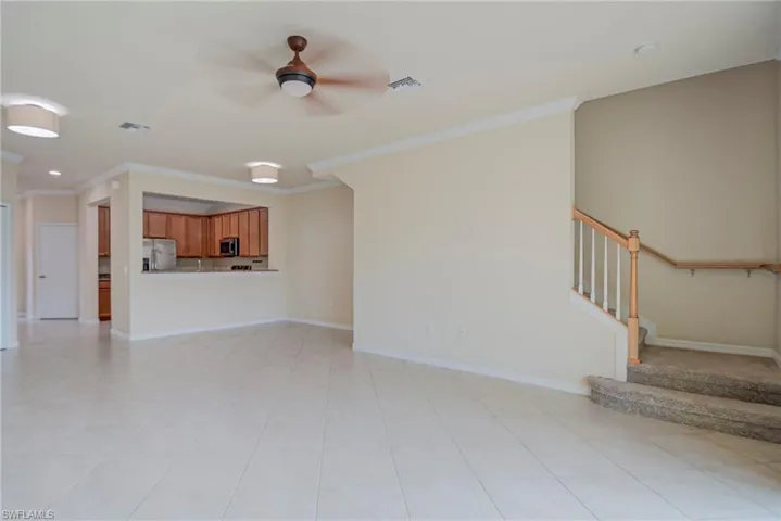 Unfurnished living room featuring ornamental molding and a ceiling fan