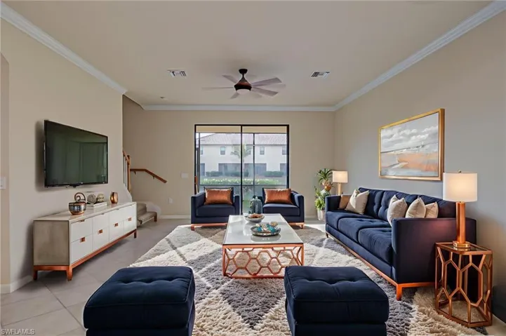 Living room with ceiling fan, ornamental molding, and light tile patterned floors