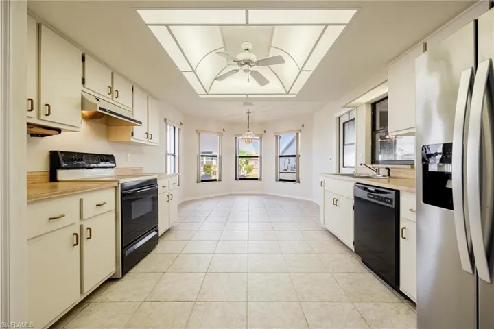 Kitchen featuring sink,  appliances, light tile patterned floors, and white cabinets