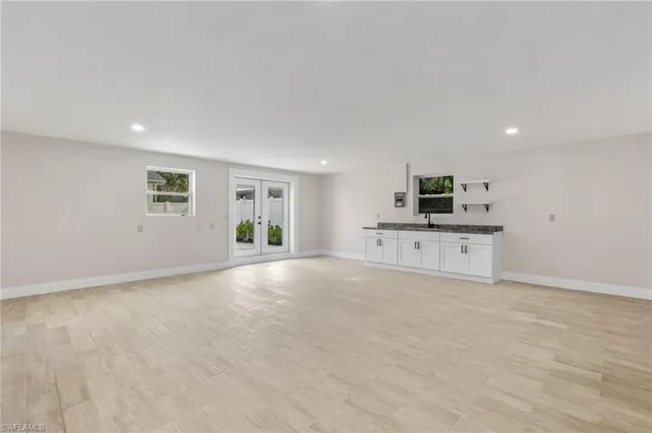 Unfurnished living room with recessed lighting, light wood-style flooring, and french doors