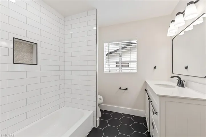 Full bathroom featuring vanity, bathtub / shower combination, and dark tile patterned floors