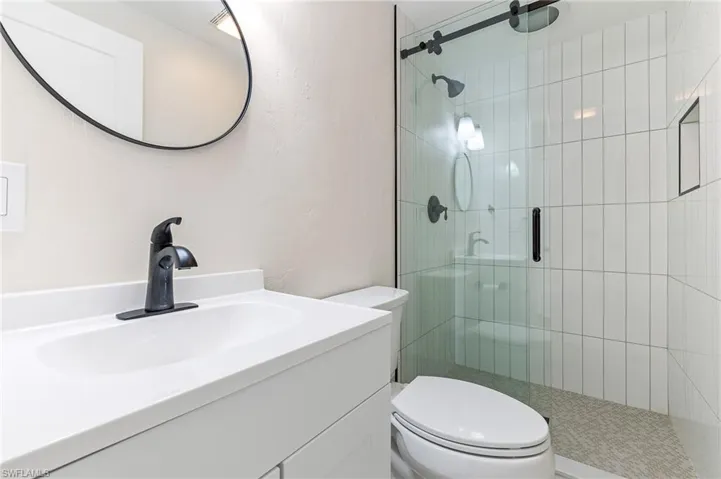 Bathroom featuring a stall shower, vanity, and a textured wall
