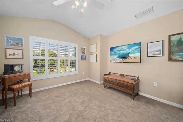 Misc room with ceiling fan, light carpet, and vaulted ceiling