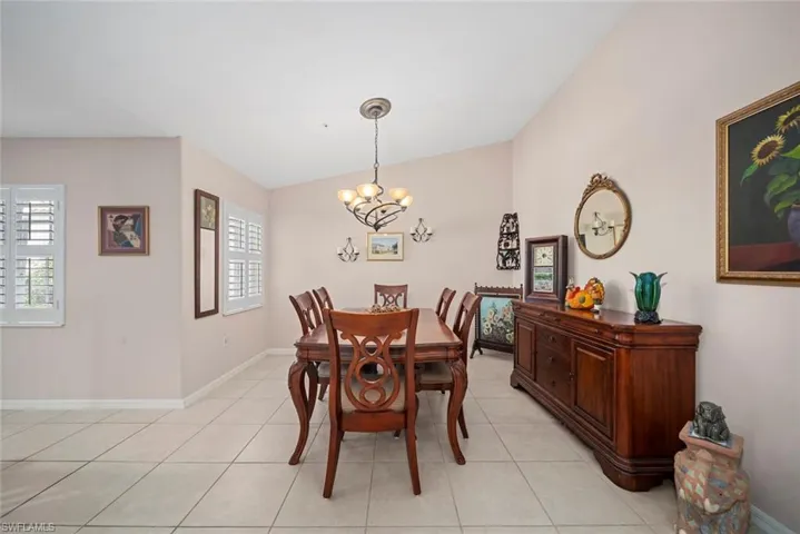 Dining area with light tile patterned floors, vaulted ceiling, and an inviting chandelier