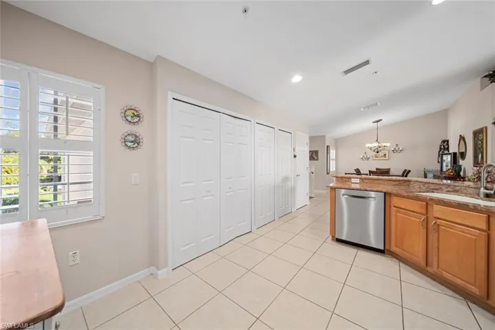 Kitchen featuring vaulted ceiling, sink, a notable chandelier, dishwasher, and hanging light fixtures