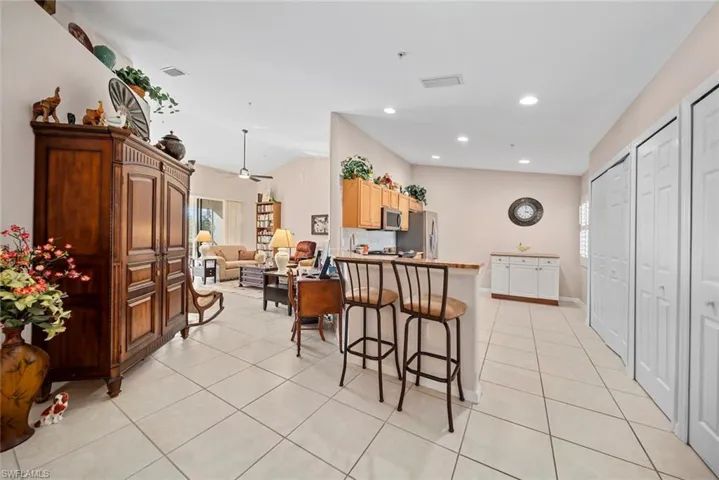 Kitchen featuring a kitchen bar, ceiling fan, light tile patterned floors, and appliances with stainless steel finishes