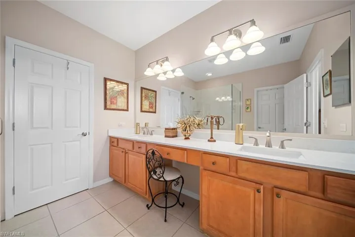 Bathroom featuring tile patterned floors, vanity, a shower with shower door, and an inviting chandelier