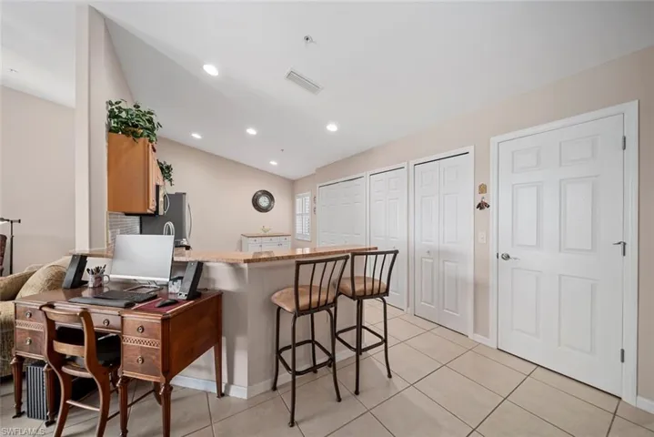 Kitchen featuring a breakfast bar, light tile patterned floors, and lofted ceiling