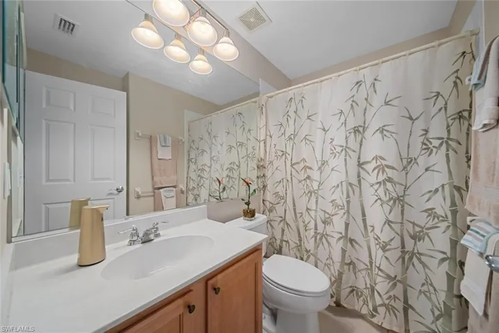 Bathroom with a chandelier, vanity, toilet, and a shower with shower curtain