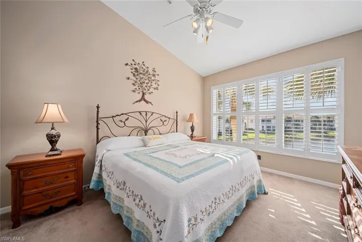 Bedroom featuring ceiling fan, lofted ceiling, and light carpet