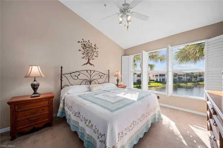Carpeted bedroom featuring ceiling fan, a water view, and high vaulted ceiling
