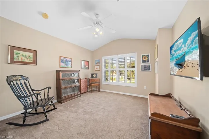 Living area with light carpet, ceiling fan, and lofted ceiling
