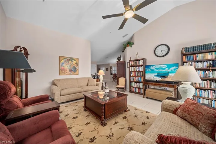 Living room featuring light tile patterned floors, ceiling fan, and lofted ceiling
